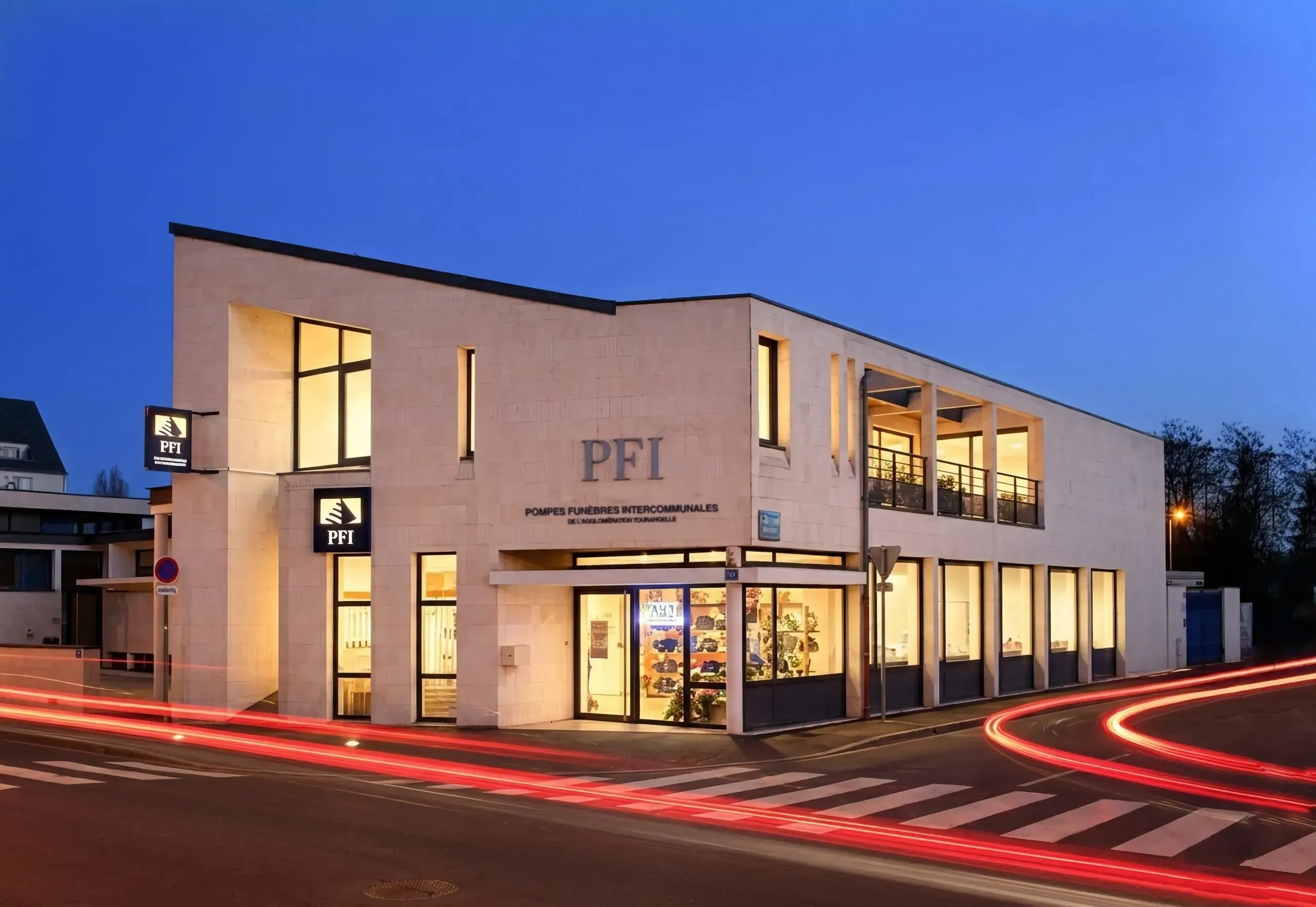 Façade illuminée de nuit de l'agence des Pompes Funèbres Intercommunales