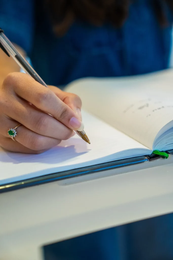 Main de femme écrivant un message d'hommage sur un livre d'or.