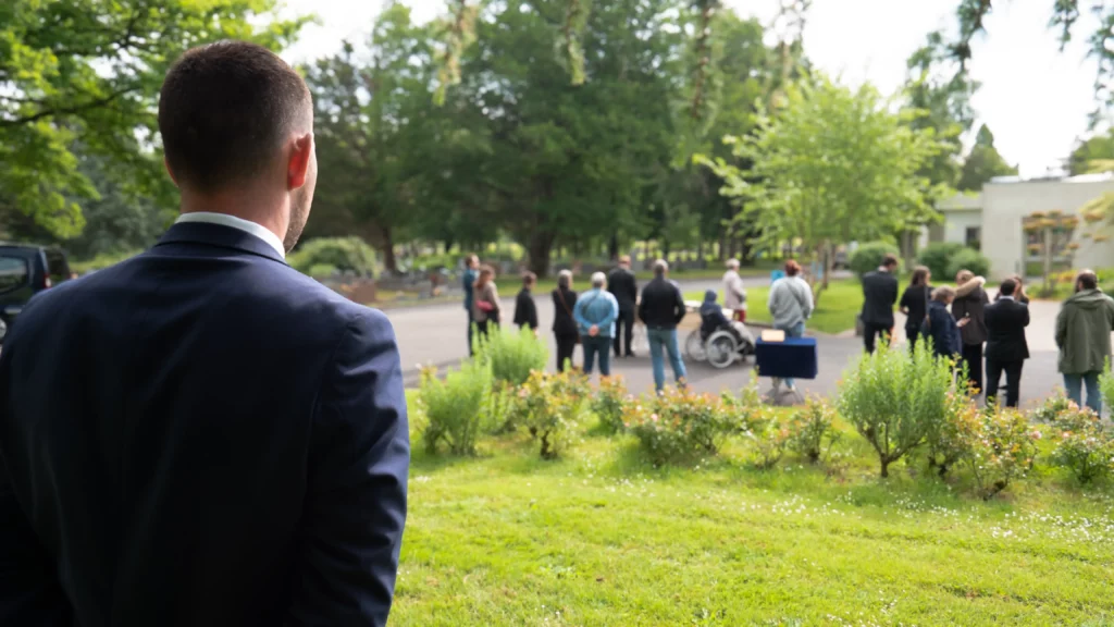 Maître de cérémonie de dos supervisant une cérémonie d'obsèques en extérieur.
