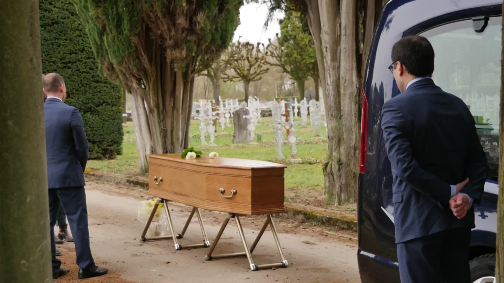 Porteurs funéraires et corbillard préparant une cérémonie dans un cimetière.
