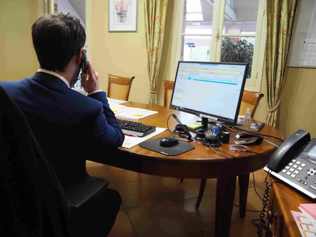 Conseiller funéraire au téléphone devant son ordinateur en agence.